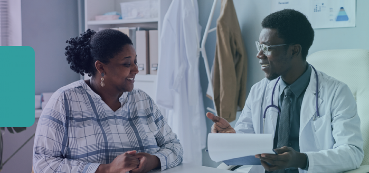 Clinician and patient reviewing paperwork together during a primary care visit focused on coordinated, value‑based care