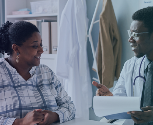 Clinician and patient reviewing paperwork together during a primary care visit focused on coordinated, value‑based care