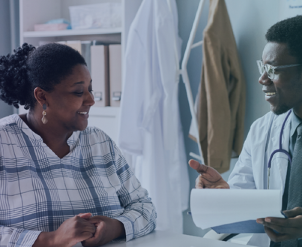 Clinician and patient reviewing paperwork together during a primary care visit focused on coordinated, value‑based care