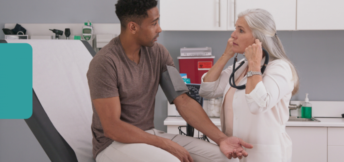 Healthcare professional using a stethoscope and blood pressure cuff to check a patient's blood pressure during a primary care appointment in a medical exam room. The patient is seated on an examination table while receiving a routine preventive health screening.