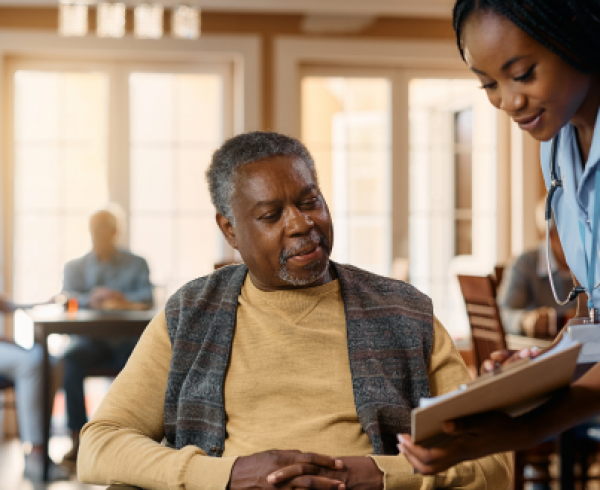 Healthcare professional reviews a care plan with an older adult in a community-based healthcare setting, illustrating patient engagement, Medicare population health management and value-based care.